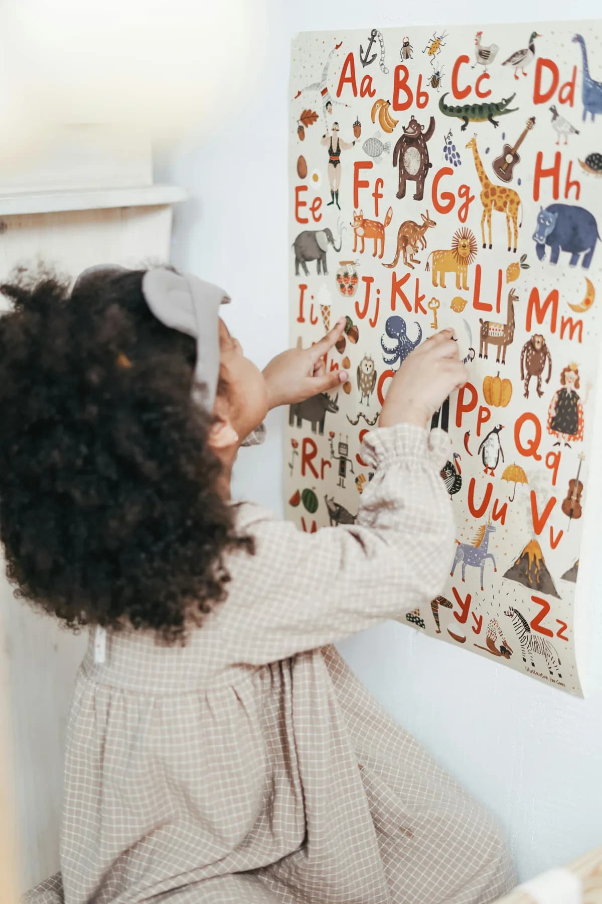 Kind zeigt auf ein Alphabet-Poster